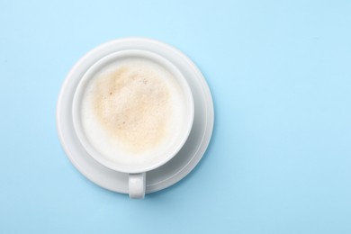 Photo of Aromatic coffee in cup on light blue background, top view. Space for text