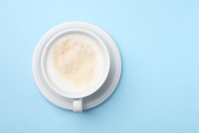 Aromatic coffee in cup on light blue background, top view. Space for text