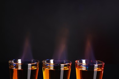 Photo of Flaming alcohol drink in shot glasses on dark background