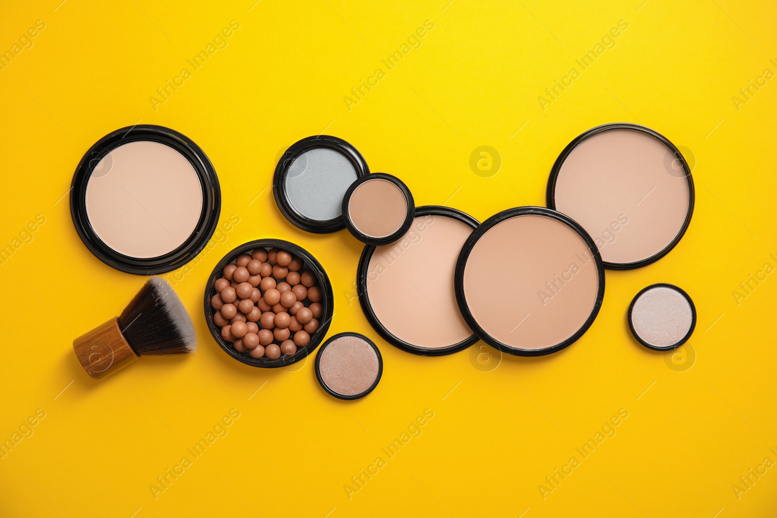 Photo of Flat lay composition with various makeup face powders on color background