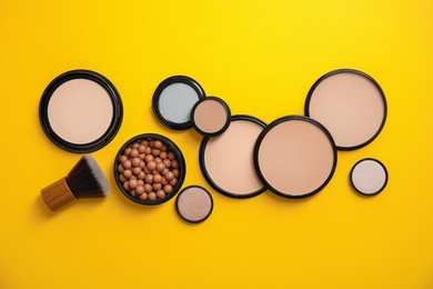 Flat lay composition with various makeup face powders on color background