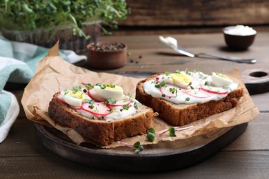 Photo of Delicious sandwiches with radish, egg, cream cheese and microgreens on wooden table