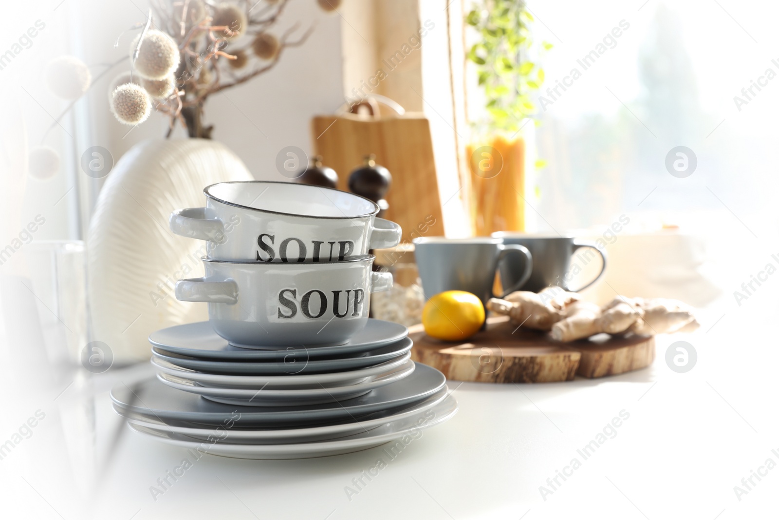 Photo of Clean dishware on white table in modern kitchen