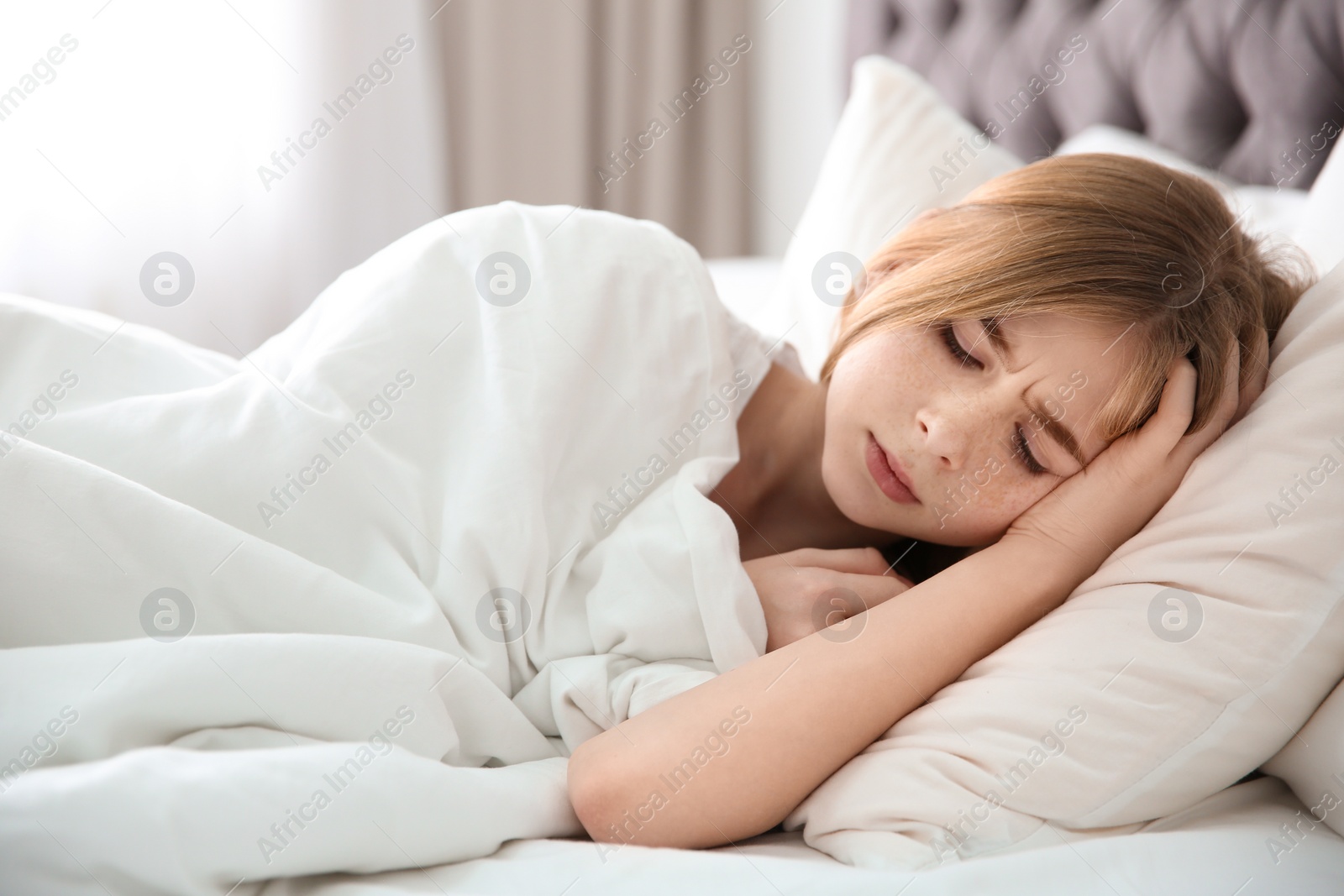 Photo of Teenage girl suffering from headache while lying in bed at home