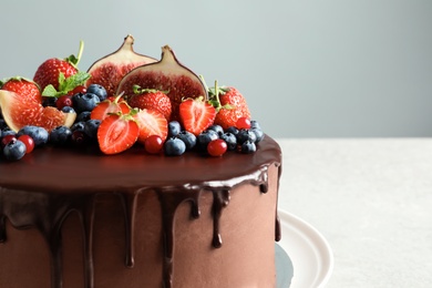 Photo of Fresh delicious homemade chocolate cake with berries on table against color background