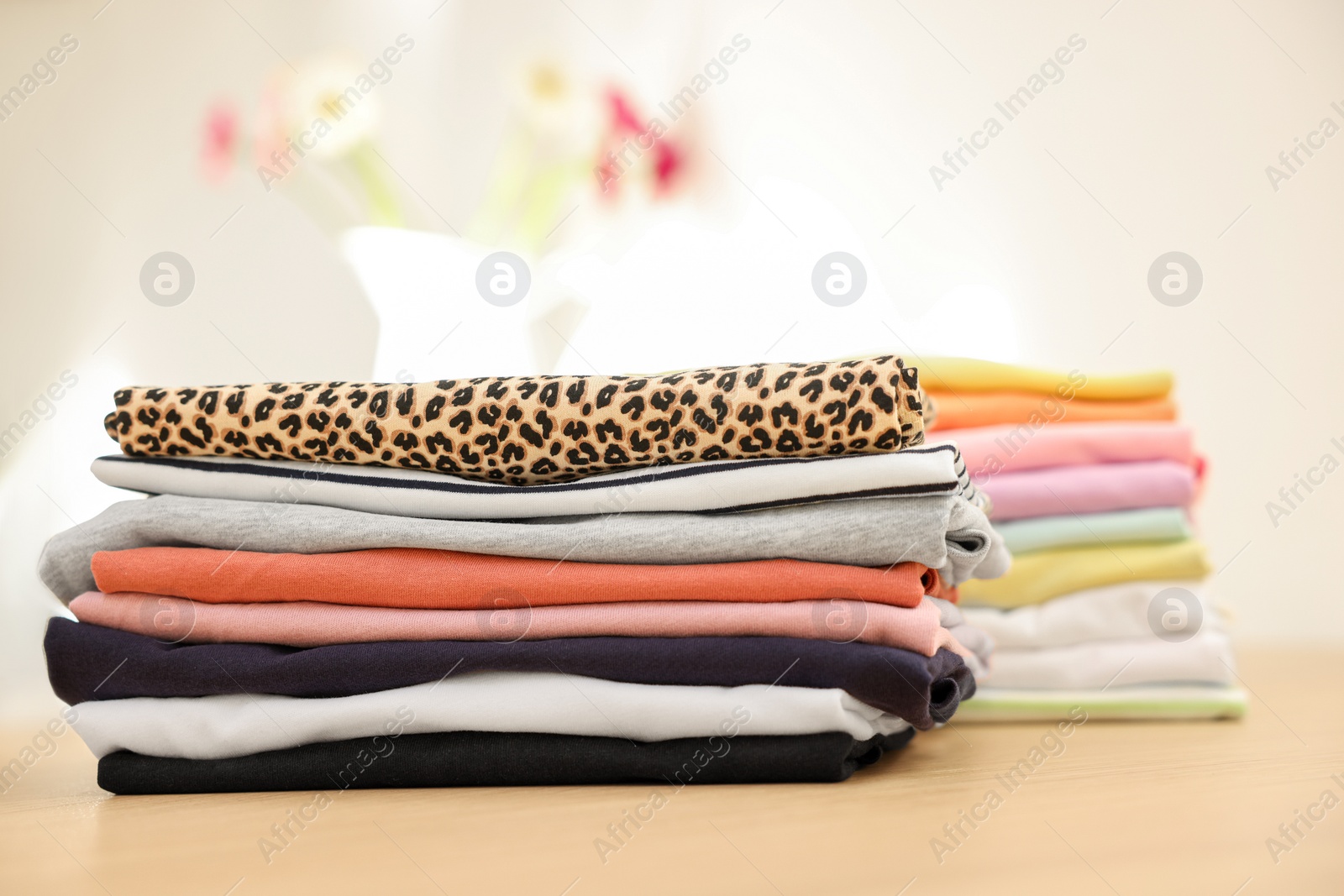 Photo of Many stacked clean clothes on wooden table