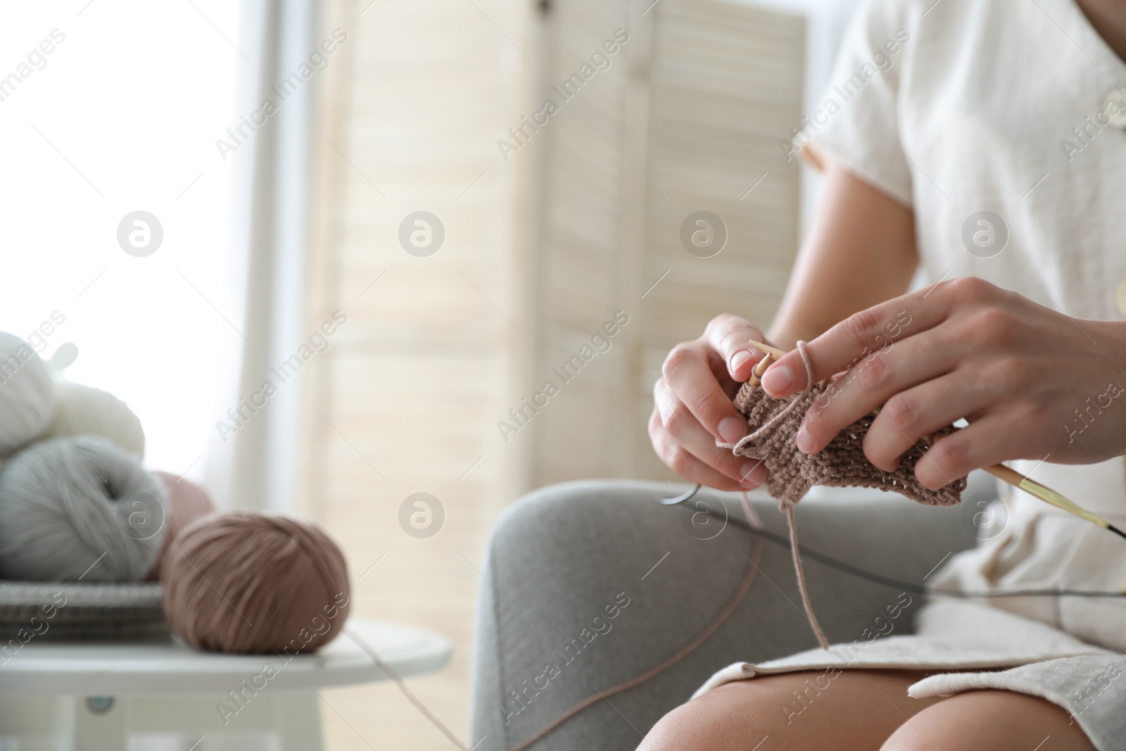 Photo of Closeup view of young woman knitting with needles indoors, space for text. Engaging in hobby