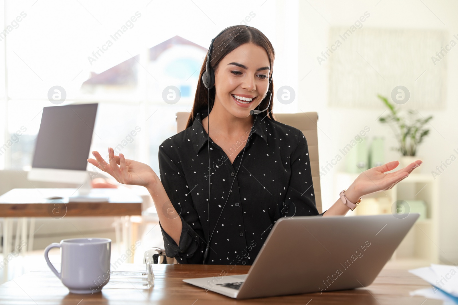 Photo of Young woman using video chat on laptop in home office