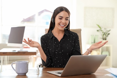 Young woman using video chat on laptop in home office