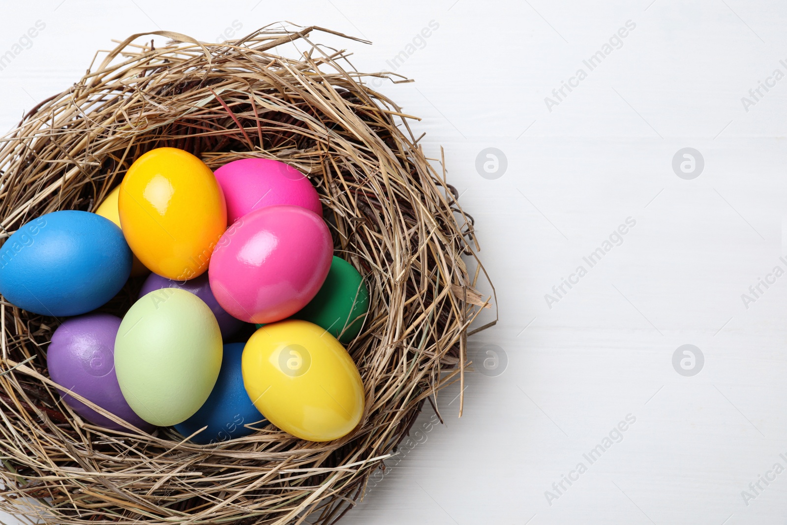 Photo of Bright painted eggs on white wooden table, top view with space for text. Happy Easter