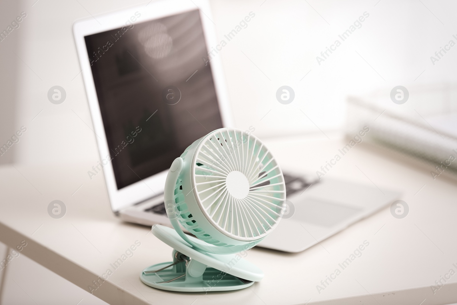 Photo of Modern electric fan and laptop on table in office