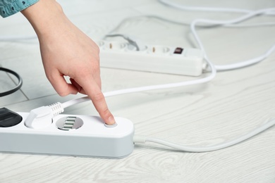 Photo of Woman pressing power button of extension cord on floor, closeup with space for text. Electrician's professional equipment