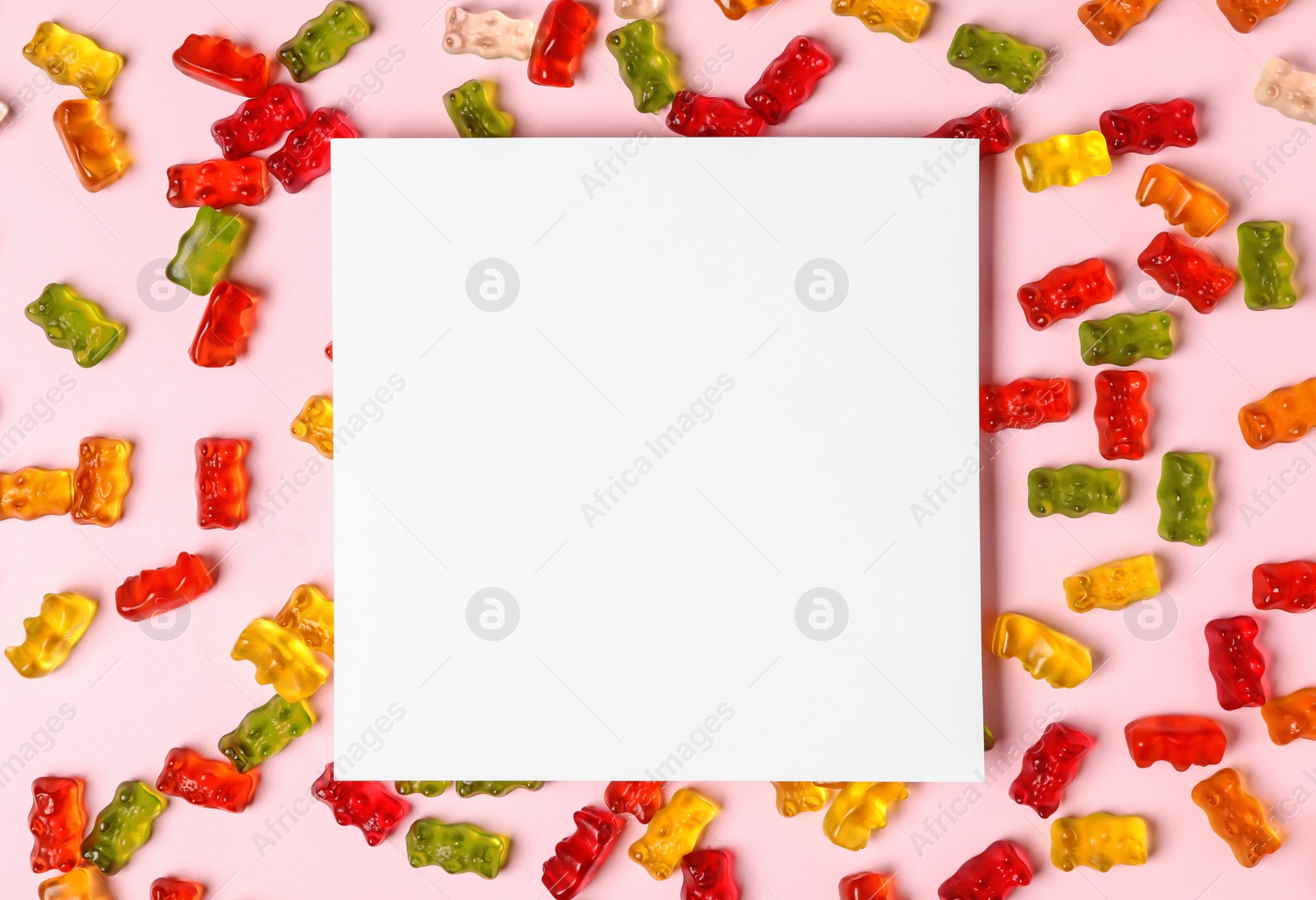 Photo of Flat lay composition with delicious jelly bears and empty card on color background. Space for text