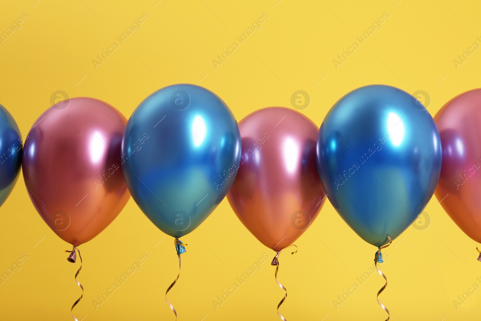 Photo of Bright balloons with ribbons on color background