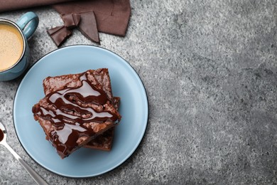 Photo of Delicious chocolate brownies with sweet syrup served on grey table, flat lay. Space for text