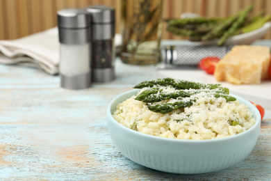 Photo of Delicious risotto with asparagus and cheese on wooden table. Space for text