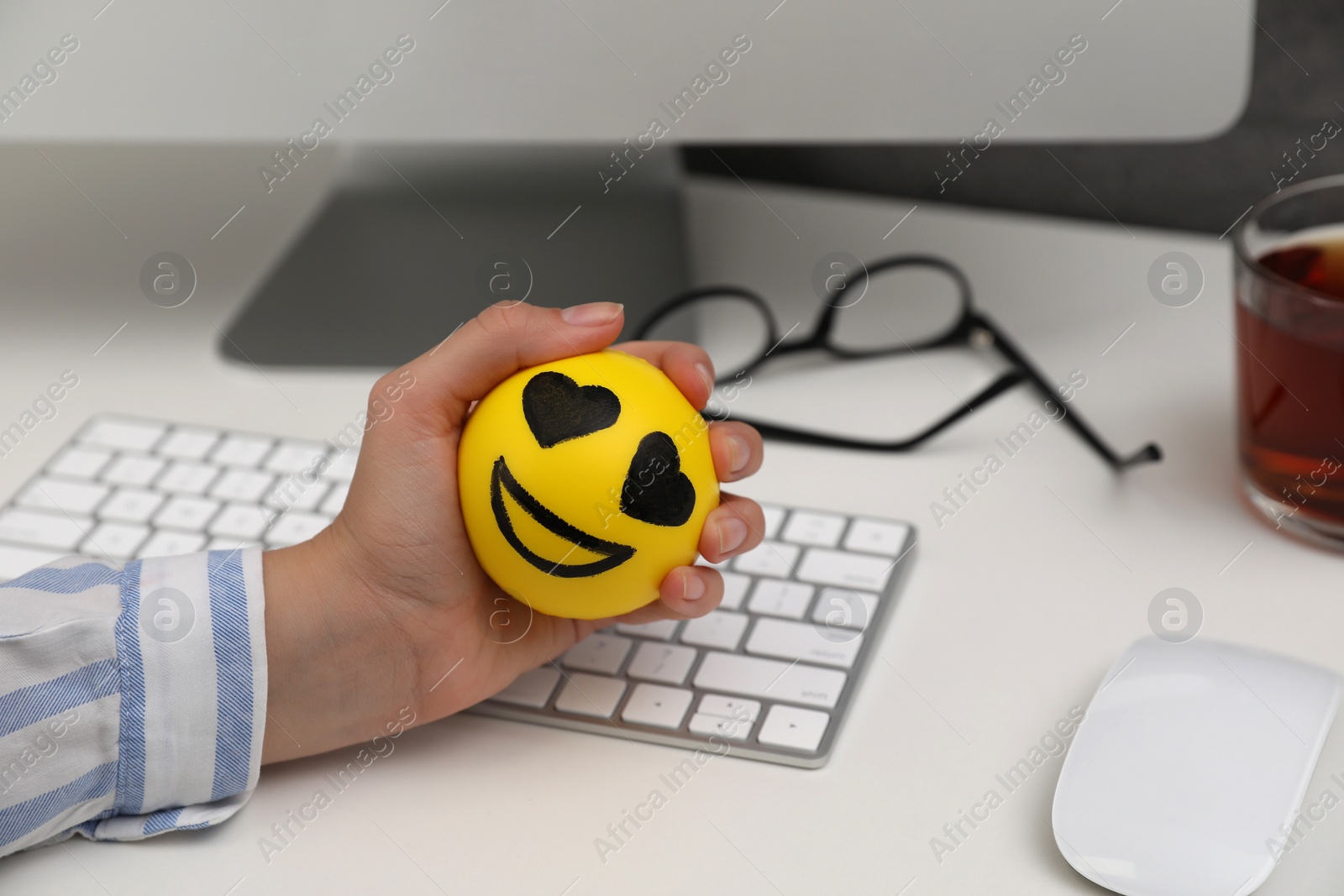 Photo of Woman squeezing antistress ball at workplace, closeup