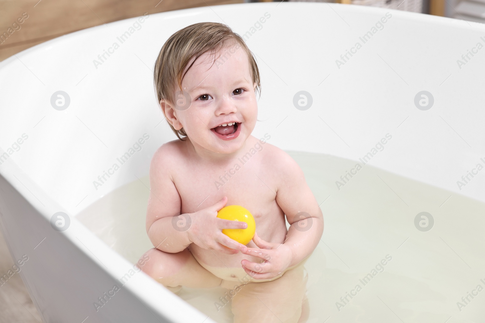 Photo of Cute little child bathing in tub at home