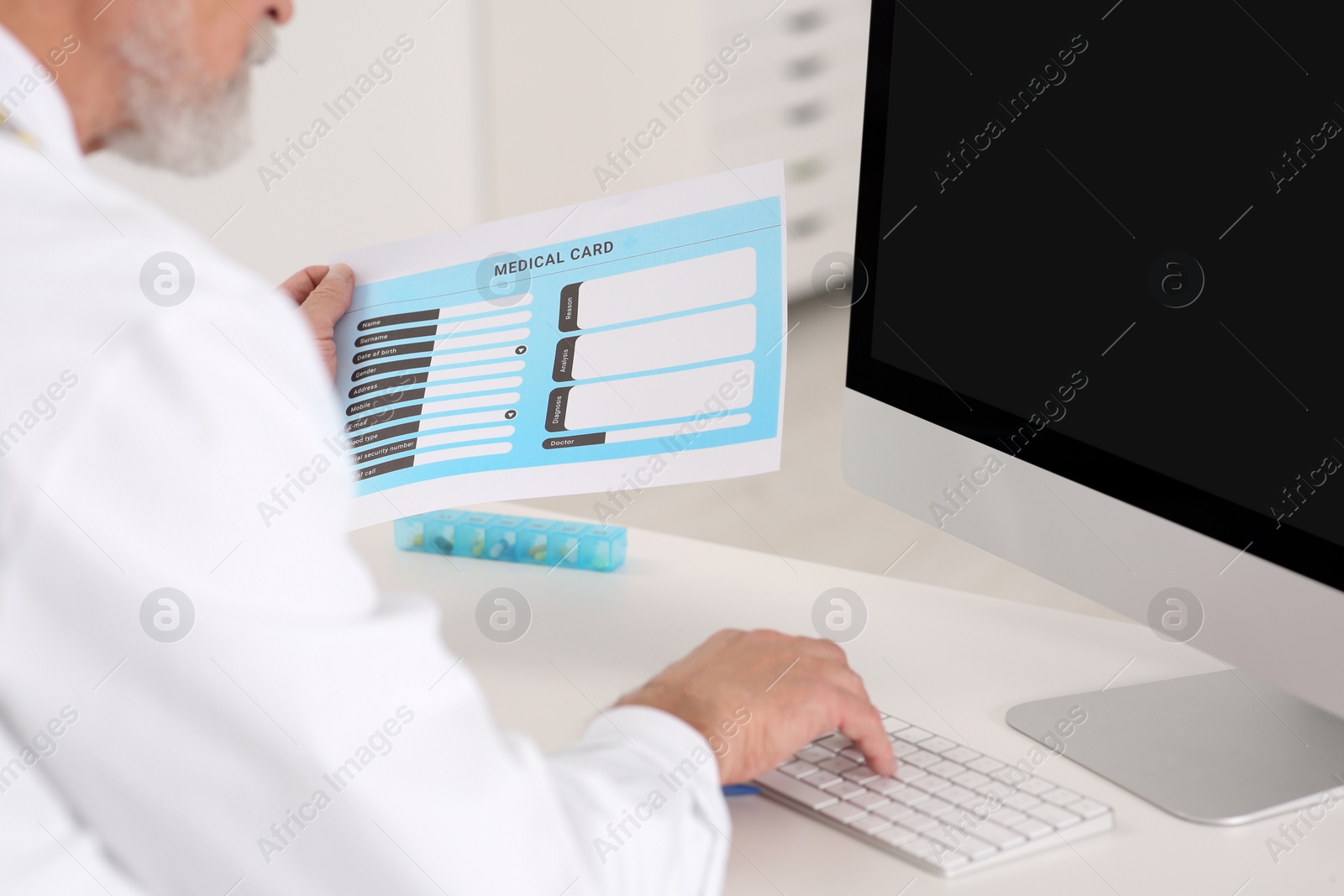 Photo of Doctor with patient's medical card at table in clinic, closeup