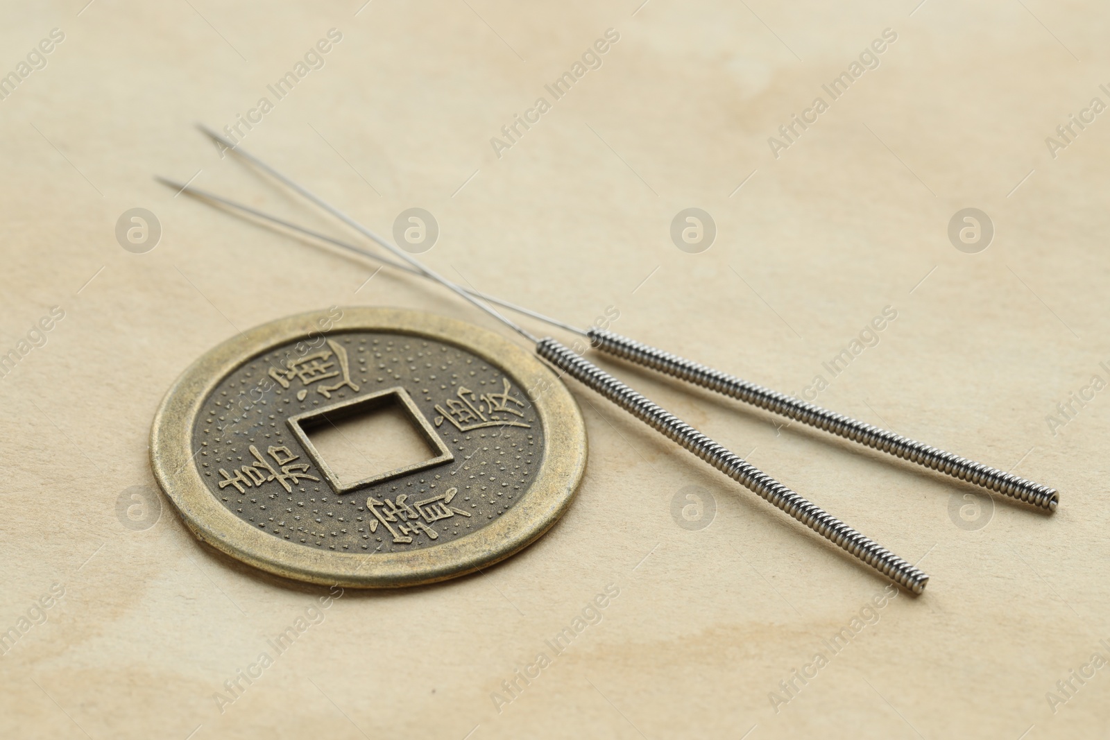 Photo of Acupuncture needles and Chinese coin on paper, closeup