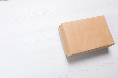 Parcel box wrapped in kraft paper on wooden background with space for text