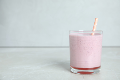 Photo of Tasty milk shake with straw on light grey table. Space for text