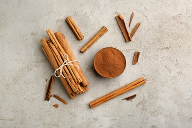 Photo of Aromatic cinnamon sticks and powder on grey table, flat lay