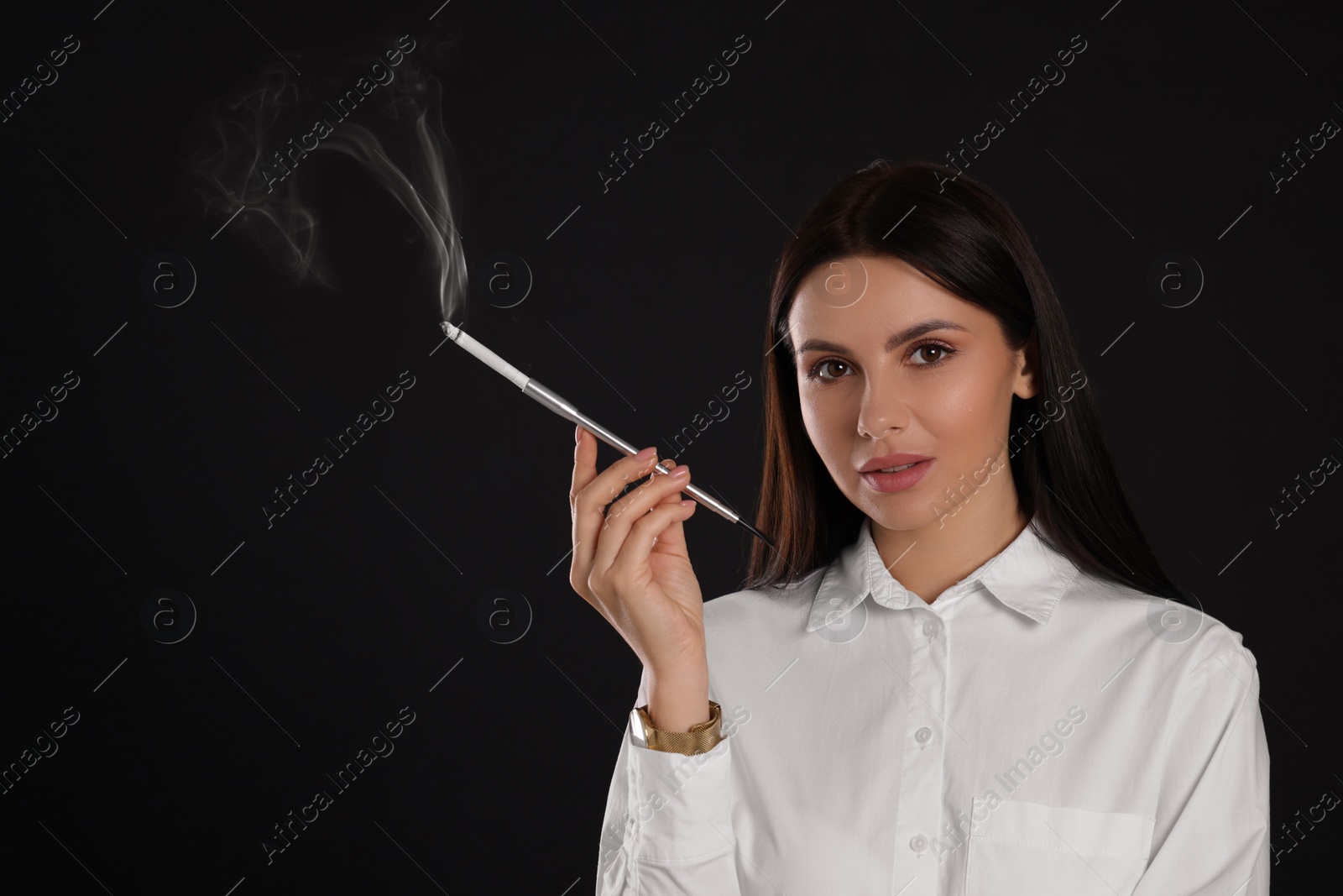 Photo of Woman using long cigarette holder for smoking on black background, space for text