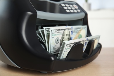 Modern electronic bill counter with money on table, closeup