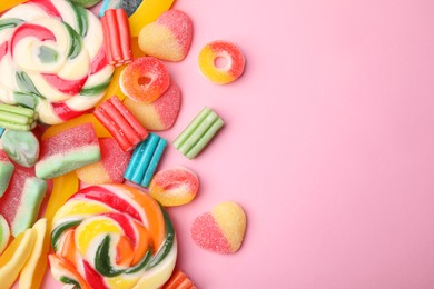 Photo of Many different jelly candies and lollipops on pink background, flat lay. Space for text