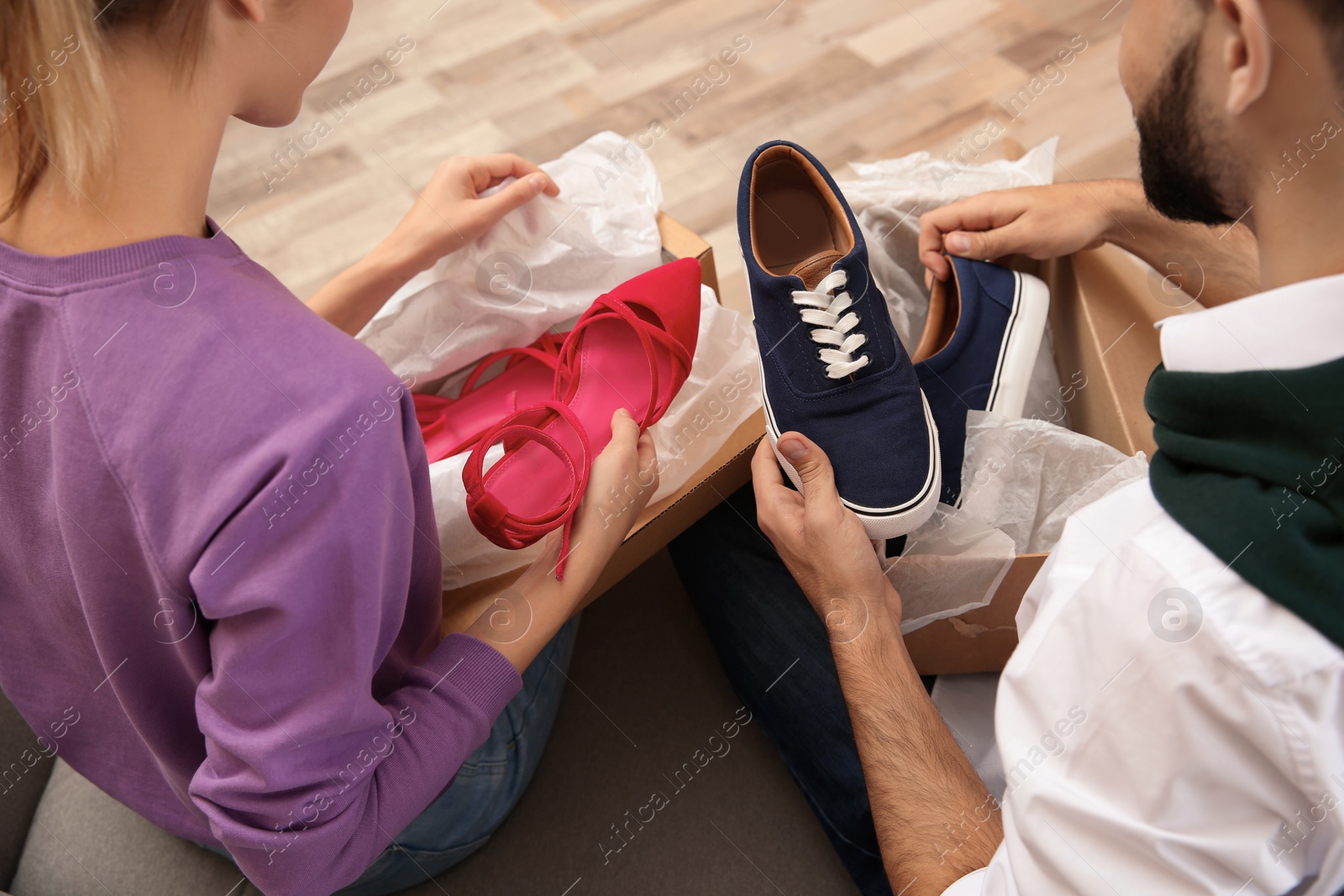 Photo of Young couple opening parcels in living room, closeup