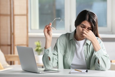 Photo of Young woman suffering from eyestrain at desk in office