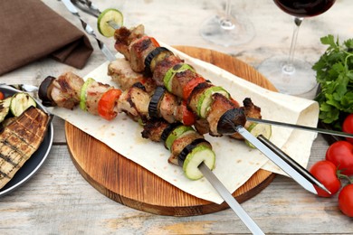 Photo of Metal skewers with delicious meat and vegetables served on wooden table