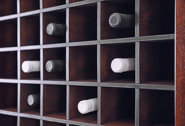 Photo of Wooden shelving unit with wine bottles, closeup