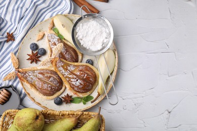 Photo of Delicious pears baked in puff pastry with powdered sugar served on white table, flat lay. Space for text