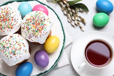 Photo of Traditional Easter cakes and painted eggs on light grey table, flat lay