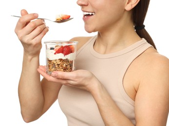 Happy woman eating tasty granola with fresh berries and yogurt on white background, closeup