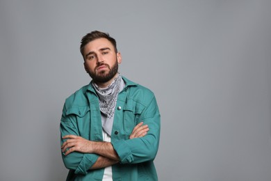 Photo of Fashionable young man in stylish outfit with bandana on grey background, space for text
