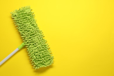 Photo of Mop with plastic handle on yellow background, top view. Space for text