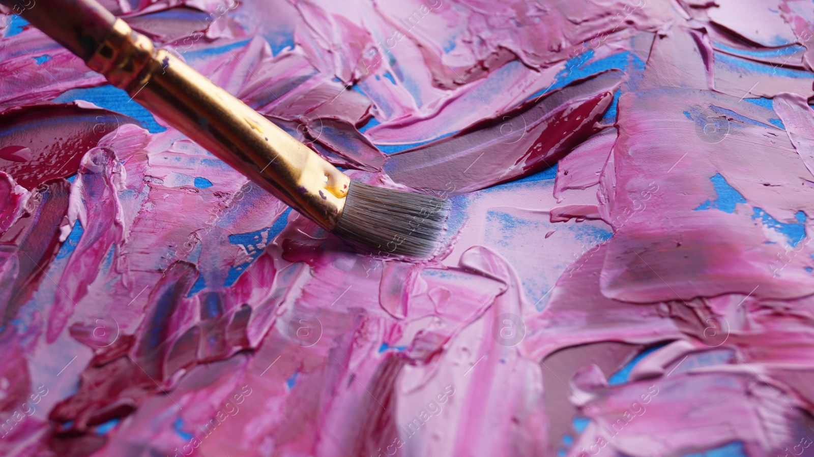 Photo of Brush on artist's palette with mixed paints, closeup