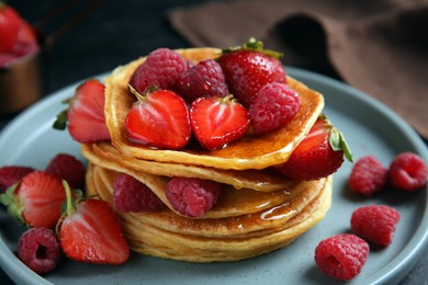Photo of Tasty pancakes with fresh berries and honey on plate, closeup