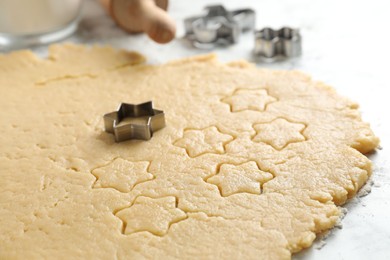Photo of Making shortcrust pastry. Raw dough and cookie cutters on table, closeup