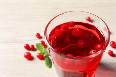 Photo of Tasty refreshing cranberry juice, mint and fresh berries on light wooden table, closeup. Space for text