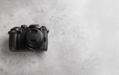 Photo of Modern camera on light grey stone table, top view with space for text. Video production industry