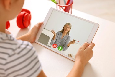 Image of E-learning. Little girl using tablet for studying online at table indoors, closeup