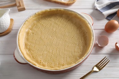 Photo of Pie tin with fresh dough and ingredients on white wooden table. Making quiche