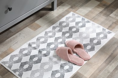 Photo of Mat with slippers near grey chest of drawers indoors