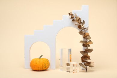 Photo of Autumn presentation for product. Geometric figures, pumpkin and golden branch with leaves on beige background