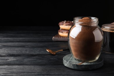 Photo of Jar of instant coffee on black wooden table. Space for text