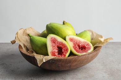 Photo of Bowl with fresh ripe figs on gray table. Tropical fruit